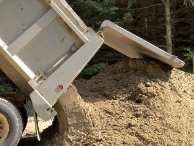 Concrete waste being dumped out of the back of a waste truck
